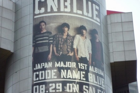 ファッションビル「渋谷109」にCNBLUEが明日29日のリリースを控えたメジャー1stアルバム「CODE NAME BLUE」の巨大ビジュアルボードが掲示されている。（2012年8月24日、東京都渋谷区）