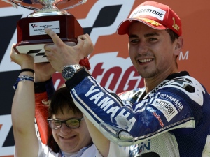新ヘルメットのカラーリングデザインを担当したダウン症の女性と共に、表彰台で勝利を喜ぶホルヘ・ロレンソ(ヤマハ) 新ヘルメットのカラーリングデザインを担当したダウン症の女性と共に、表彰台で勝利を喜ぶホルヘ・ロレンソ(ヤマハ)