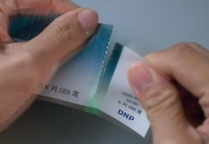 大日本印刷は、切る、折り曲げるなどの圧力をかけるとインキが発光する「応力発光印刷」を開発した。写真は、ミシン目を切った時に発行している様子(同社発表資料より) 大日本印刷は、切る、折り曲げるなどの圧力をかけるとインキが発光する「応力発光印刷」を開発した。写真は、ミシン目を切った時に発行している様子(同社発表資料より)