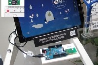 センサーそのものは写真上部に載せたように5×5mm四方。これを地中に埋めて無線通信で土壌環境をスマートフォンやタブレットなどで確認できる。ディスプレーモニター右の電子体温計のような装置は、先端に装着したセンサーを鉢植えやベランダの植栽などの土壌に挿してその状態測定を行なう簡易機器のプロトタイプ。