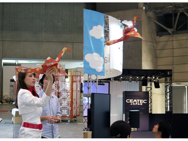 「ORIZURU」を手に飛行させるコンパニオンの向こう側で真剣な表情の男性が、開発に協力した超小型飛行体研究所の宗像俊龍氏