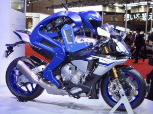 ヤマハのMoToGPマシン「YZF-R1M」にまたがる「MOTOBOT」。まだ体重移動はできないが、アクセル、ブレーキ、ギアチェンジはバイクの改造無しで操作可能。 ヤマハのMoToGPマシン「YZF-R1M」にまたがる「MOTOBOT」。まだ体重移動はできないが、アクセル、ブレーキ、ギアチェンジはバイクの改造無しで操作可能。