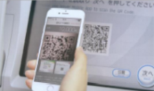 ATMにスマートフォンのQRコードを読み取らせているところ。（セブン銀行発表資料より）
