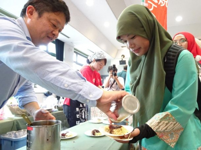 オタフクソースが開発した「ハラールお好みソース」を試食するムスリム留学生。(画像: オタフクソースの発表資料より)