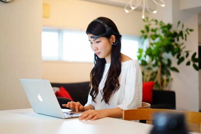 ヘッドギア型脳波計を装着した女性。脳波データを元にシステムが感情を推定する（写真：電通サイエンスジャムの発表資料より）