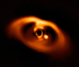 原始惑星系ディスクPDS70　ここで発見された惑星の一つが画面中央の黒円からやや右下側に写っている明るい円盤上の存在である。(c) ESO/A. Müller et al.