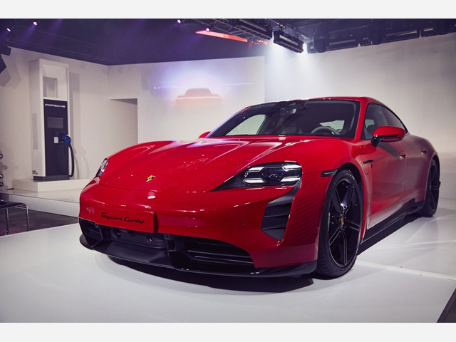 東京・表参道で報道陣に公開したポルシェ初のピュアEV「タイカン」、左奥に見えるのは次世代CHAdeMO対応の急速充電器、タイカンのバッテリーを30分で80%まで充電する