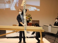 全国各地で入社式の中止が相次ぐ中、恒例のカンナ掛け入社式を「分散型」で実施したアキュラホーム。ロボットによる非接触の辞令交付などの工夫を凝らし、新入社員の門出を祝った。