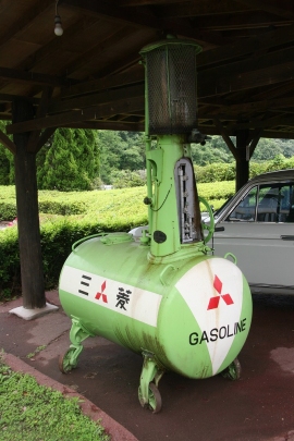 Phot：昔懐かしい可搬式丸形ガソリン計量機、奥には2代目410型系ブルーバードが見える（画像提供：糸目今日子）