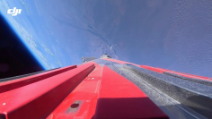 ロケットの赤いフィン越しに機体後方を捉えた搭載カメラの映像。上昇する機体の背後に、宇宙の暗闇と地球の丸みが浮かび上がる (Dji.com)