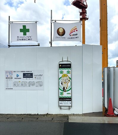 【プレサンスグループ】株式会社メルディアDCが建設現場の看板に緊急時の「担架」に変わる救護器具兼用看板「タンカん板」を設置