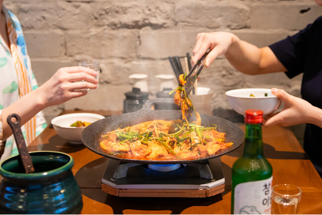 タッカンマリ食べ放題の「晴レ時々タッカンマリ食堂」に山盛りのセリを豪快に崩して味わう新感覚の鉄板鍋”旨辛タッコギ鉄板鍋”が夏の看板メニューとして新登場！7月24日から。