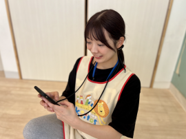スマートフォンで園児情報を確認する保育士 スマートフォンで園児情報を確認する保育士